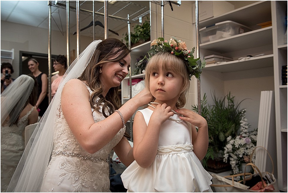 bride helping flower girl with necklace