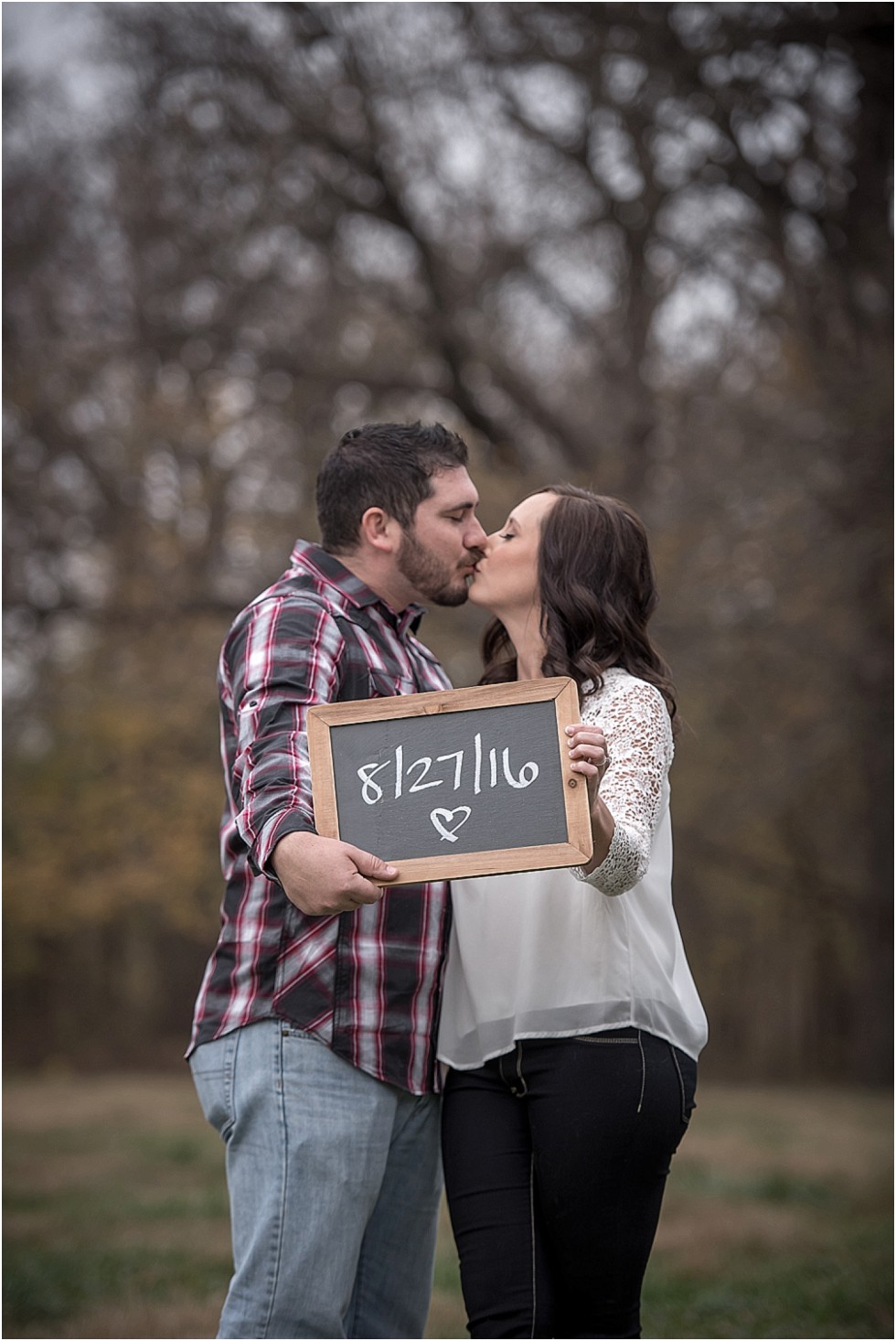 couple posing with chalk board with wedding date 