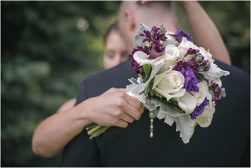close up of bride holding bouquet around groom's neck