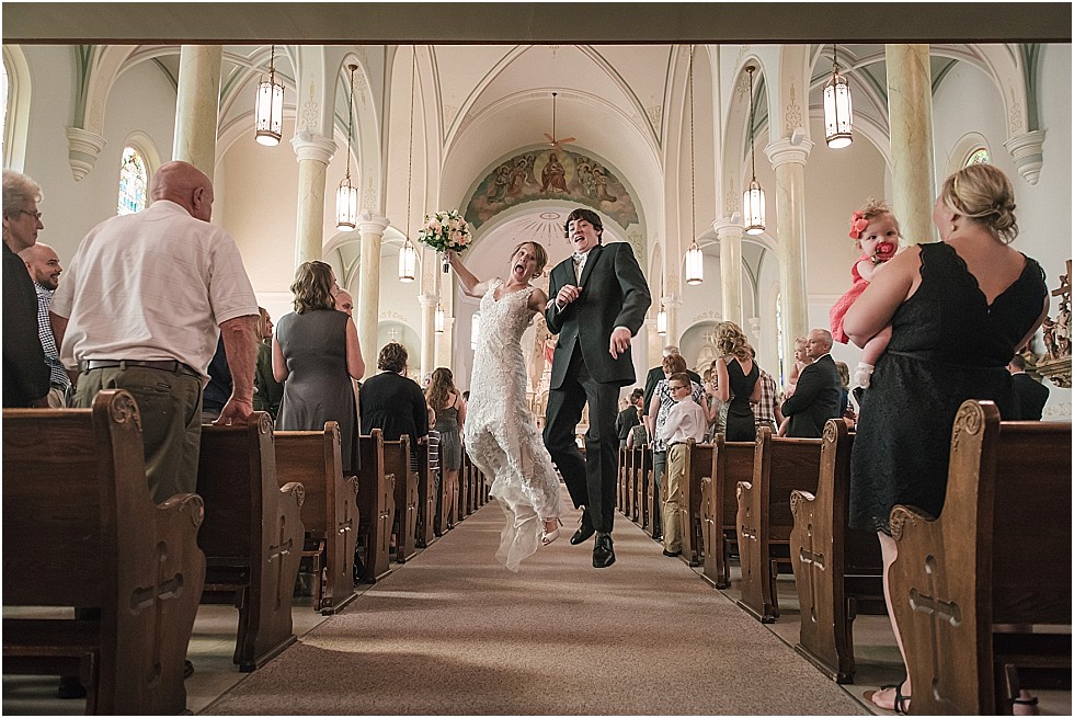 bride and groom leaping while walking down aisle