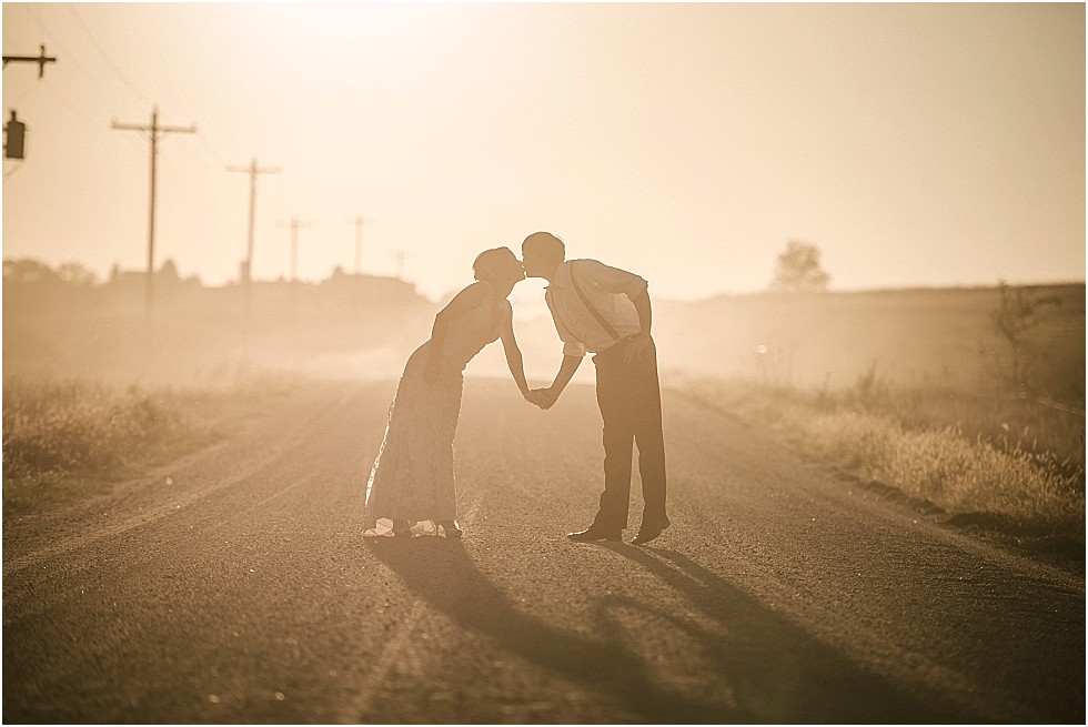 bride and groom kiss on dusty gravel road