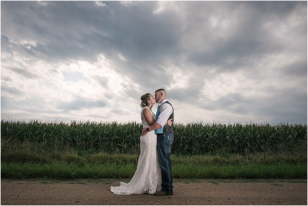 bride and groom kissing on a country road