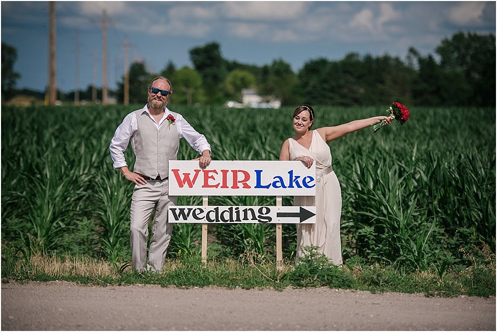 bride and groom pose by sign